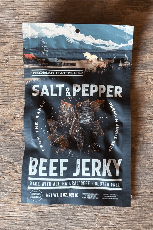 Packaging of Thomas Cattle salt and pepper beef jerky on a wooden surface