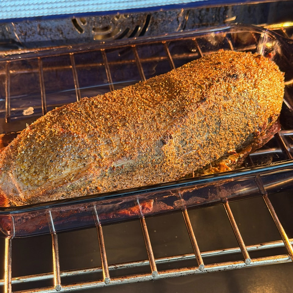 Beef roast in an oven with visible seasoning