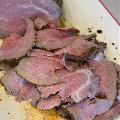 Sliced roast beef on a white plate with a red rim