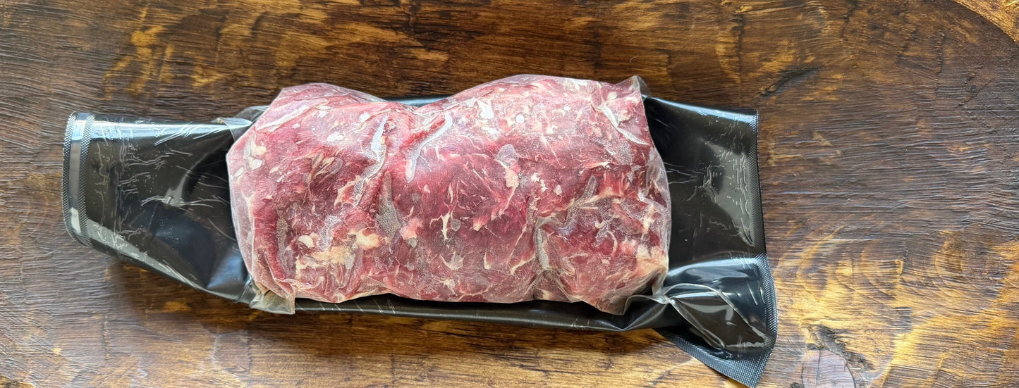 Raw meat on a wooden cutting board with a black background