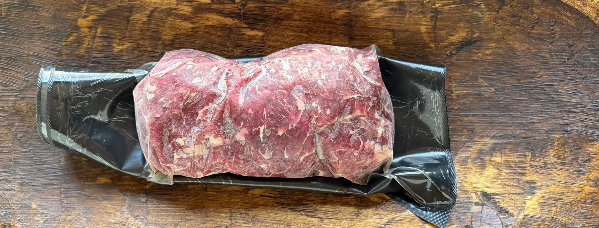 Raw meat on a wooden cutting board with a black background