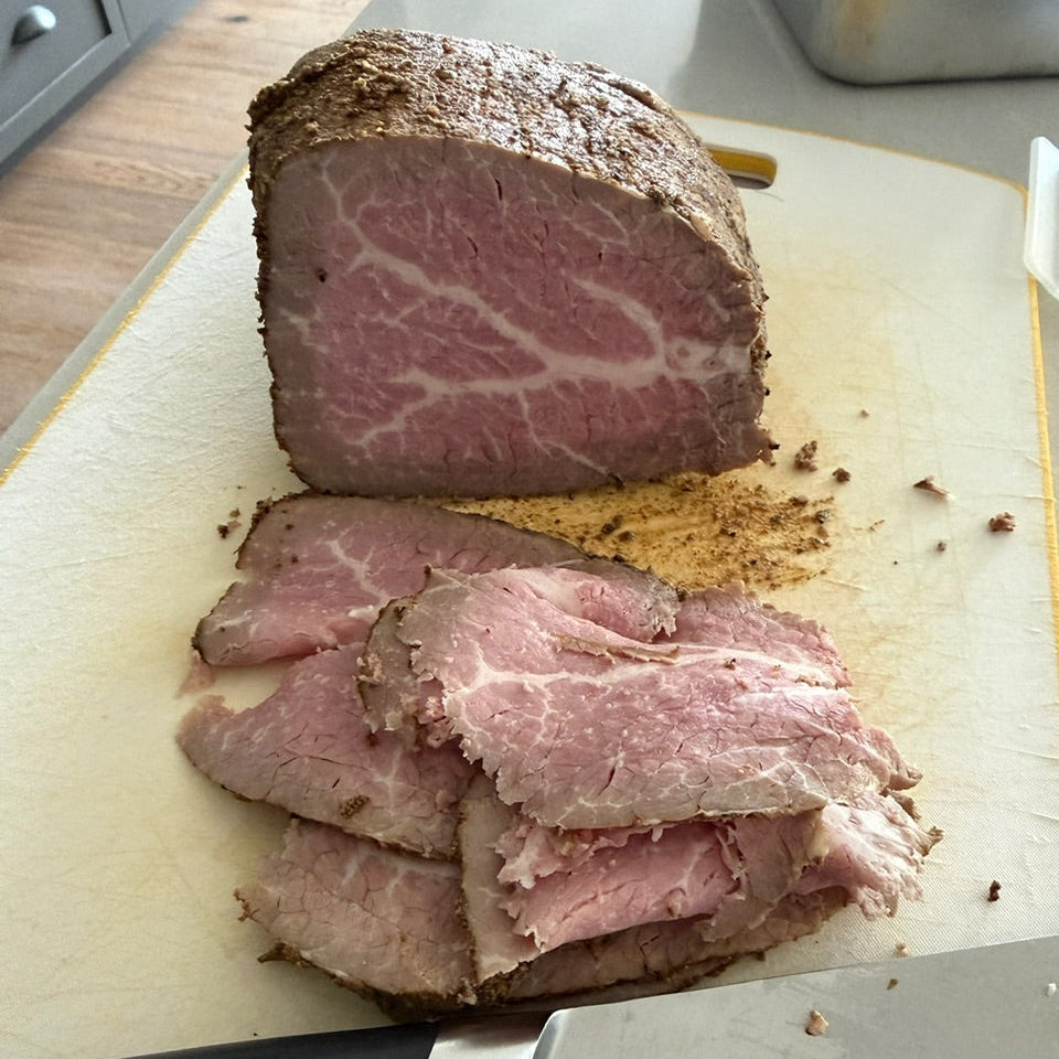 Sliced roast beef on a cutting board with a knife