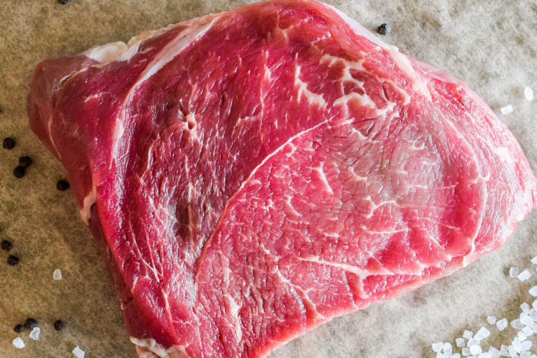 Raw steak on a surface with salt and pepper