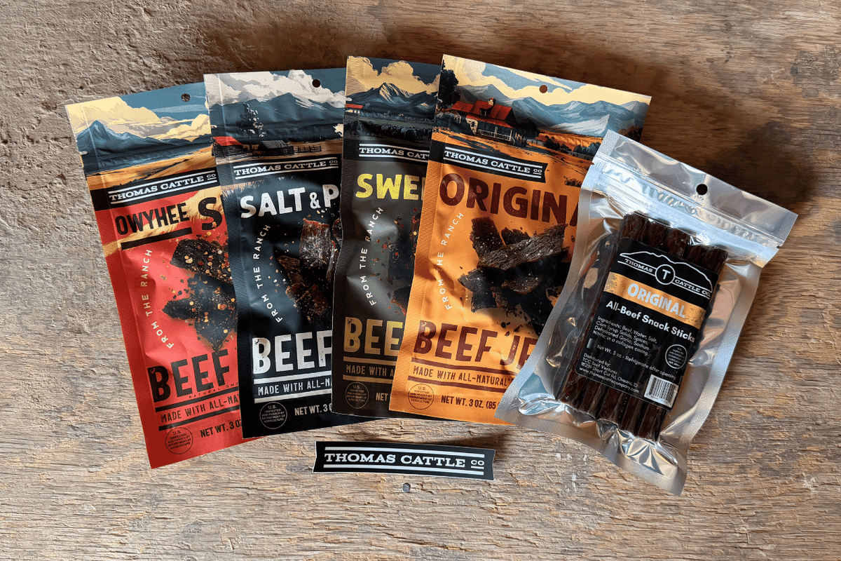 Assorted packages of Thomas Cattle beef jerky on a wooden surface